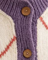 Cárdigan tejido de punto con diseño de rombos, en colores crema, violeta y detalles en rojo. Presenta cuello redondo, cierre frontal con botones de madera y textura acanalada en los bordes.