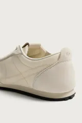 Zapatilla de cordones fabricada en piel con acabado serraje y combinación de piezas de tejido, con suela dentada en contraste de color y pespuntes decorativos.