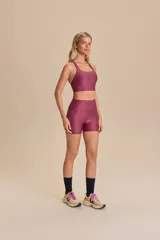 Top deportivo negro con tirantes finos cruzados en la espalda y relleno extraíble. Fabricado en tejido Allure® con tecnología LYCRA® ADAPTIV, ofrece elasticidad, adaptándose al cuerpo y realzando la figura.