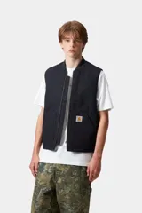 Chaleco de trabajo Carhartt WIP, color azul marino, con cierre frontal completo, cuello tipo bomber y bolsillos delanteros. Presenta el logo de la marca bordado en el pecho.