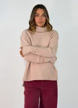 Sweater de cuello alto en color beige, confeccionado en tejido de punto con detalle de costura vertical central. Presenta mangas largas con puños acanalados y un ruedo con terminación acanalada, con un diseño de corte ligeramente más largo en la parte posterior.