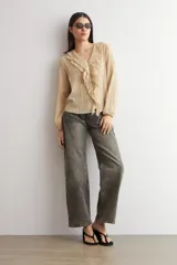 Blusa color beige de manga larga, con escote en V adornado con volados y cierre frontal con botones.