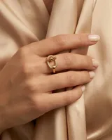 Anillo de acero quirúrgico dorado con diseño ovalado y aplique transversal, decorado con circones en su estructura.