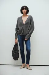 Cárdigan gris de punto con cuello en V, cierre frontal con botones y bolsillos de parche.