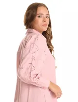Camisa de color rosado con cuello clásico y cierre frontal de botones. Presenta mangas largas con detalles calados y puños anchos abotonados.