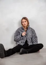 Campera puffer con estampado animal print en tonos gris y negro, cuello alto y cierre frontal.