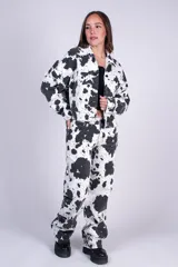 Campera corta de denim con estampado tipo animal print de vaca en color blanco y negro, con cuello camisero, cierre frontal de botones metálicos y bolsillos con solapa en el pecho.