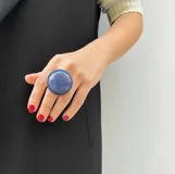 Anillo de diseño minimalista con una media esfera de resina azul brillante. Cuenta con una base de acero ajustable.