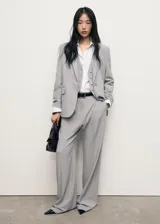 Pantalón de sastreria gris con diseño de raya diplomática, de tiro bajo, corte recto y amplio con pinzas delanteras y trabillas para cinturón.