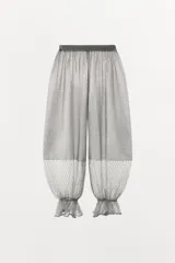 Pantalón abombacho semitransparente de tejido de encaje suave color gris, con tiro medio, cintura elástica y diseño con calados y volantes en los tobillos.