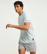 Remera deportiva de hombre con tecnología dry fit, cuello redondo y manga corta. Presenta un diseño liso en color beige con una pequeña etiqueta decorativa en el dobladillo.