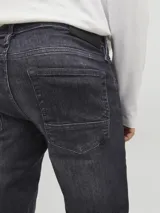 Jean de corte slim con tiro bajo, confeccionado en denim de color negro con efecto lavado. Presenta diseño clásico de cinco bolsillos y cierre frontal con botón.
