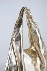 Cartera de cuero vacuno con pelo en diseño animal print similar a piel de ciervo, silueta triangular y asa integrada.