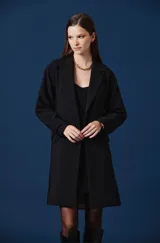 Saco largo de mujer con diseño de doble botonadura, solapas clásicas y mangas largas con detalle de trabillas en los puños. Presenta una silueta estructurada y fluida, ideal para un look sofisticado.