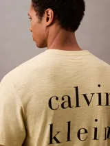 Remera color crema de algodón con cuello redondo y mangas cortas con dobladillo. Estampado vertical con el logo de Calvin Klein Jeans en el frente.