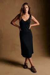 Vestido midi de tejido acanalado color negro, con escote en V y breteles finos ajustables con lazo en los hombros. Presenta un corte al cuerpo y diseño minimalista.