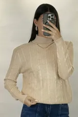 Buzo de hilo de punto con diseño de trenzas verticales, cuello alto y cadena metálica decorativa incorporada en la parte frontal.