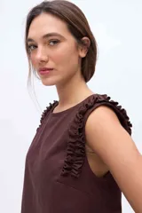 Musculosa negra con cuello redondo y detalles de volados en los hombros, confeccionada en una mezcla de algodón y Tencel.