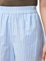 Short de tiro alto con cintura elástica, confeccionado en tejido plano a rayas verticales celestes y blancas. Presenta un acabado foil que le da un efecto brillante.