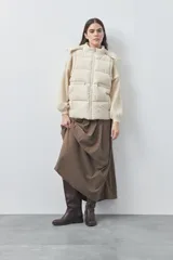 Chaleco puffer negro con diseño acolchado, capucha desmontable y cierre frontal. Cuenta con cordones ajustables en la cintura y bolsillos laterales.