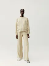 Pantalón de jogging color beige, de corte recto y tiro alto, con bolsillos laterales, costuras verticales al frente y cordón ajustable en la cintura.