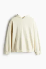 Canguro color crema de algodón pesado con efecto lavado. Modelo holgado con capucha cruzada de doble capa, hombros caídos, bolsillo canguro, puños y bajo en punto acanalado.