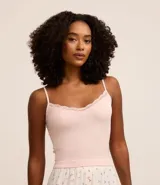 Blusa de pijama de tirantes finos ajustables, confeccionada en tejido seamless acanalado color rosado. Presenta un delicado detalle de encaje en el escote.