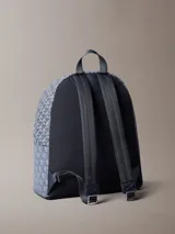 Mochila de poliéster reciclado con estampado de logo jacquard en tonos azul y gris. Presenta asa de mano superior, correas acolchadas ajustables, cierre de cremallera y bolsillo frontal con cremallera.