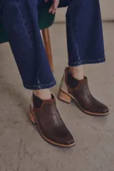 Botineta de diseño tricolor con cuerpo en tono beige, panel elástico lateral negro y talón con textura símil reptil en color marrón. Presenta un taco cuadrado robusto de color negro.