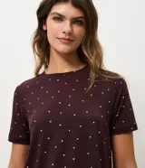 Blusa de pijama de manga corta y cuello redondo, de color marrón oscuro con estampado integral de pequeños corazones blancos. Confeccionada en tejido peach touch de poliéster y elastano.