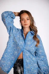 Camisa celeste con bordado de flores blancas, de manga larga abullonada.