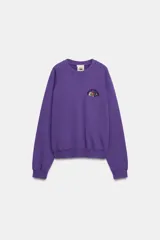 Sudadera lavada Fruit of the Loom, color morado, de cuello redondo con detalle de costura triangular, manga larga y calce holgado. Presenta un pequeño bordado con el logo de la marca en el pecho y acabados en rib elástico en cuello, puños y ruedo.