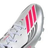 Championes de fútbol Adidas modelo F50 Messi Club, diseñados para terreno firme y césped artificial. Presentan una capellada sintética en color blanco con detalles en plateado, negro y fucsia, incluyendo la inscripción Messi en el lateral y las icónicas tres tiras de la marca.