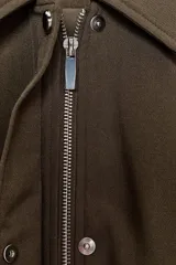 Chaqueta bomber color marrón, con cuello solapa, cierre frontal oculto con cremallera y botones a presión. Presenta mangas remangadas con trabillas y bajo abullonado con elástico interior.