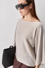Sweater de punto liviano negro, con escote bote y mangas amplias de largo tres cuartos que aportan una silueta relajada y fluida.