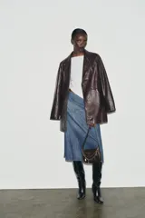 Camiseta de cuello barco y manga larga con diseño asimétrico en el bajo. Presenta un corte entallado con cierre lateral mediante cremallera oculta.