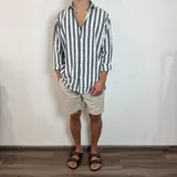 Camisa de lino de corte oversize con diseño de rayas verticales en tonos blanco y tostado, manga larga y cierre frontal con botones.