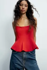 Top negro de escote redondo con tirantes finos y diseño peplum.