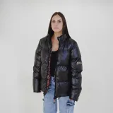 Campera puffer reversible de color negro con acabado brillante. Presenta cuello alto, cierre frontal y un diseño interior con estampado animal print. Incluye logo de la marca en la manga.