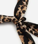 Pañuelo cuadrado de satén con estampado animal print de leopardo. Incluye una argolla metálica para facilitar su anudado y estilizado.