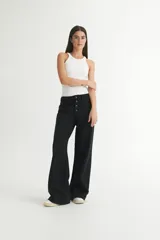 Pantalón de jean negro, de corte holgado desde la cadera hasta el bajo, con tiro medio y cierre frontal con botones.