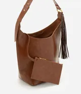 Bolso tipo bucket grande Satinato en color marrón, confeccionado en PU. Presenta asa de hombro ajustable, herrajes metálicos dorados, detalle de borla decorativa lateral con textura símil serpiente y un pequeño monedero o estuche removible con cierre unido por una tira.