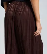 Pantalón de corte aladino confeccionado en viscosa y poliéster, con diseño de rayas verticales y acabado con leve transparencia. Presenta cintura alta, trabillas para cinturón y puños elásticos en el dobladillo.