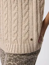 Sweater de tejido grueso con textura trenzada, cuello alto y mangas largas.