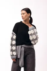 Sweater de punto con cuerpo liso en color negro y mangas largas tejidas en crochet gris con aplicaciones de flores en relieve color blanco.