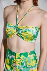 Top strapless con estampado floral en tonos verde y amarillo, con tirantes finos al cuello y detalle de nudo en el centro del busto.