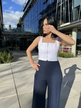 Blusa blanca con cierre frontal de cremallera plateada, corte ajustado y breteles anchos.