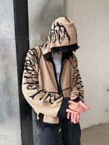 Hoodie con cierre frontal, confeccionado en tejido de punto 100% algodón. Es una prenda reversible con diseño de estampado gráfico en mangas y capucha, y presenta detalles de roturas intencionales en puños, ruedo y bolsillos.