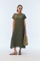 Vestido largo evasé de lino color verde militar, con escote redondo, mangas cortas con dobladillo vuelto y ruedo asimétrico.