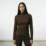 Polera de manga larga color marrón, con cuello alto y costuras decorativas frontales que crean un diseño de panel. Presenta un pequeño bordado circular en el centro del pecho.